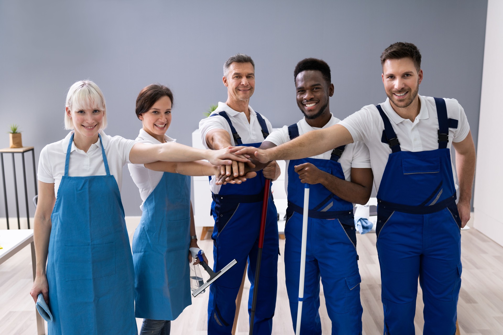 Smiling Diverse Janitors Stacking Hands